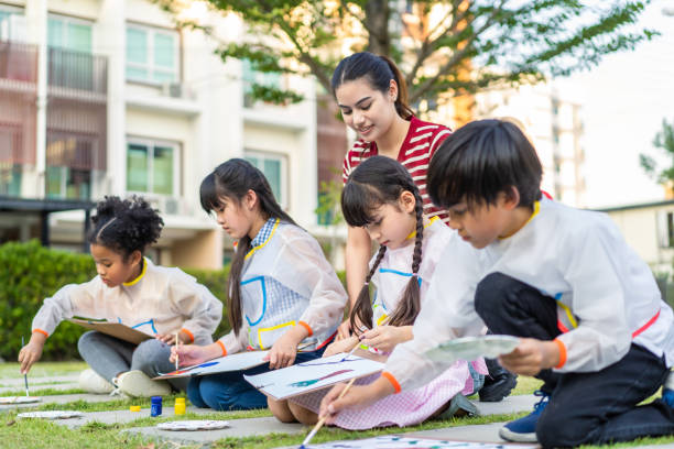 학교 정원에서 야외에서 칠하는 학생 그룹. 사랑스러운 아이들은 초등학교에서 수채화 물감과 붓으로 예술 그림을 그리는 법을 배웁니다. - child art and craft latin american and hispanic ethnicity little boys 뉴스 사진 이미지