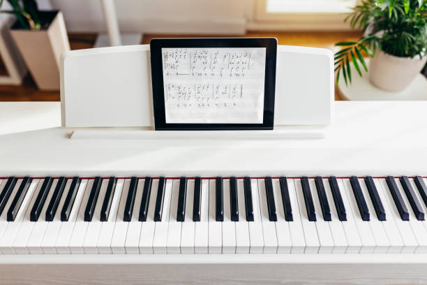 вид на часть пианино с цифровым планшетом в качестве ноты. - электропиано стоковые фото и изображения
