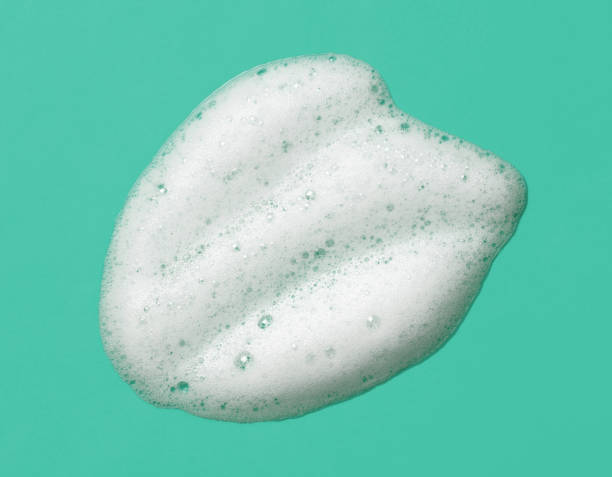 Foam lather texture background. White cleanser gel, shaving foam, shampoo bubbles on mint green color. stock photo