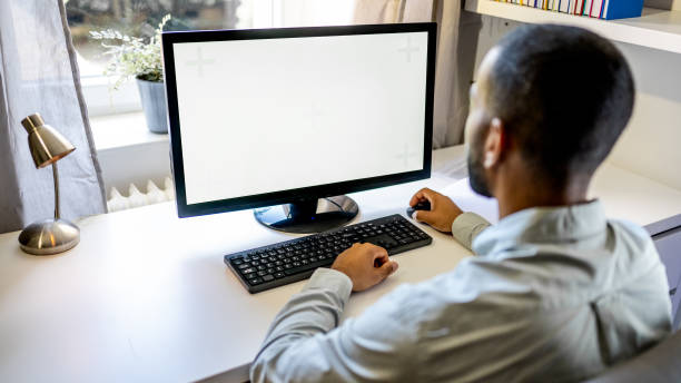 Man using computer monitor Man working on white screen of computer monitor in home office. computer mouse on table stock pictures, royalty-free photos & images