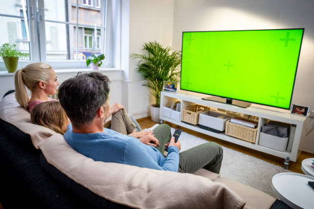 Family watching TV Family watching green screen of TV while sitting on sofa in living room. television show stock pictures, royalty-free photos & images