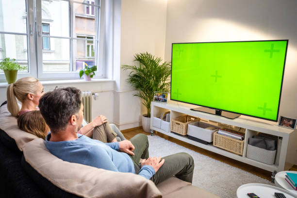 Family watching TV Family watching green screen of TV while sitting on sofa in living room. television show stock pictures, royalty-free photos & images