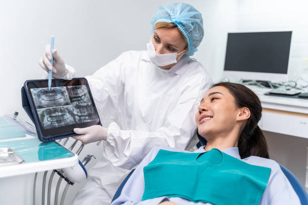 el dentista explica el cuidado bucal desde la radiografía de los dientes hasta el paciente en la clínica dental. atractiva paciente acostada en silla dental recibe tratamiento dental del médico durante el servicio de cita de procedimiento en el hospital - medical exam dental hygiene caucasian mask fotografías e imágenes de stock