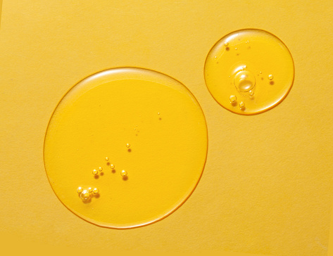 Cosmetic serum gel beauty drop on yellow background. Skincare beauty product with bubbles texture