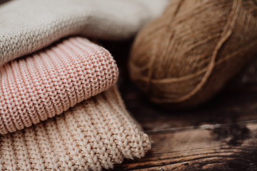 The pile of knitted sweaters on dark brown background