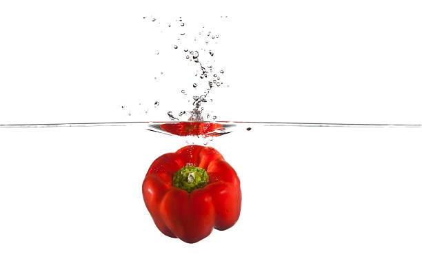 Red Bell Pepper falling into water splashing stock photo