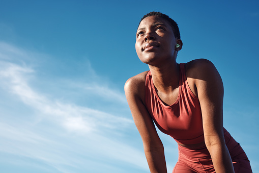 Black woman, exercise or tired after training, running or workout for balance, wellness or health outdoor. Sky, African American female, runner or athlete relax, breathing or focus for cardio or rest