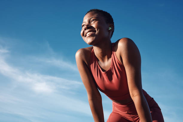 fitness, donna nera e atleta felice sorridono dopo l'allenamento di corsa, esercizio fisico e maratona. cielo blu, sport estivi e corsa di un corridore africano che respira con felicità dallo sport all'aperto - fitness apparel foto e immagini stock