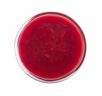 Glass bowl with liquid red berry sauce as dressing for meat, food. Top view