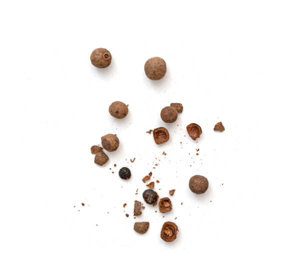 Mix of whole and broken pieces of black pepper, peppercorns or allspice isolated on white, top view stock photo