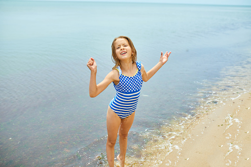 Happy, joyful little girl run on the beach, sea family vacation, Resort fun by the sea