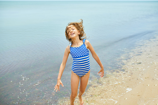 Happy, joyful little girl run on the beach, sea family vacation, Resort fun by the sea