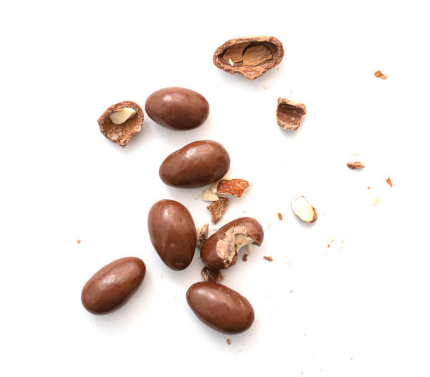 Round  and broken small chocolate candies with almond, nuts as filling isolated on white, top view stock photo