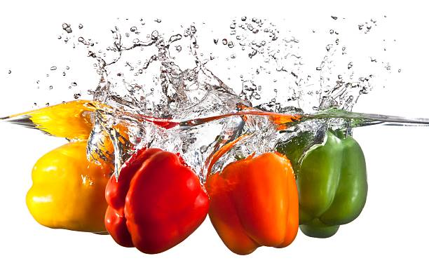 Four Bell Peppers falling into water splashing stock photo