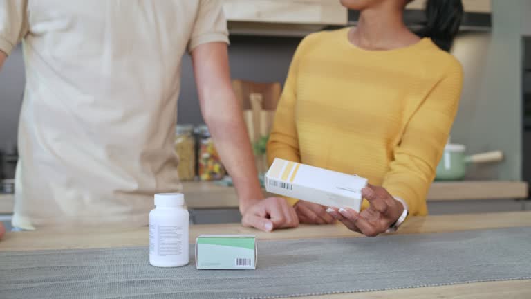 Woman telling a young man about his medicine in his kitchen