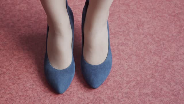 The woman approaches and stops. Close-up on the legs in blue shoes