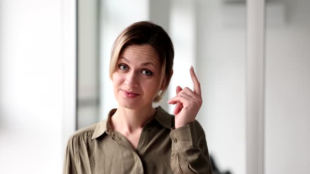 Portrait of young office woman smiling and showing gesture to think