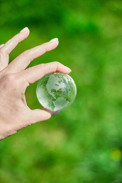 istock Human hand hold glass Earth globe on green grass background, Saving environment concept. 1468164851