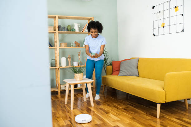 istock Young woman using mobile app to adjust her robotic vacuum cleaner 1468165596