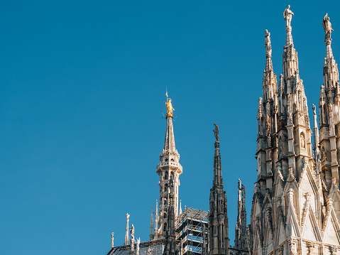 Madonnina golden statue on top of Milan Cathedral. Blue sky in the background.