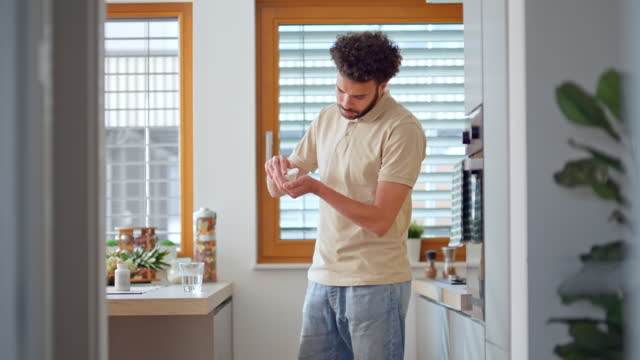 Young man taking his medicine in the kitchen