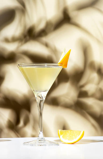 istock Vesper, classic alcoholic cocktail drink with dry gin, vodka, aperitif, lemon zest and ice. Light beige background, hard light, shadow pattern 1468173977
