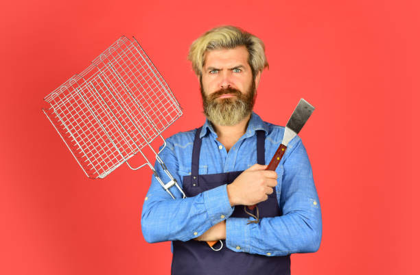 istock Cooking utensils. Summer picnic. Bbq american tradition. Hipster dyed beard promoting bbq equipment. Cooking healthy. Bbq food. Culinary concept. Tools roasting meat. Man in apron hold barbecue grill 1468174202