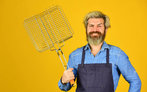 istock happy hipster hold cooking utensils for barbecue. bearded man chef. Tools for roasting meat outdoors. Picnic and barbecue. ready for barbecue party. Culinary concept. summer weekend 1468174305