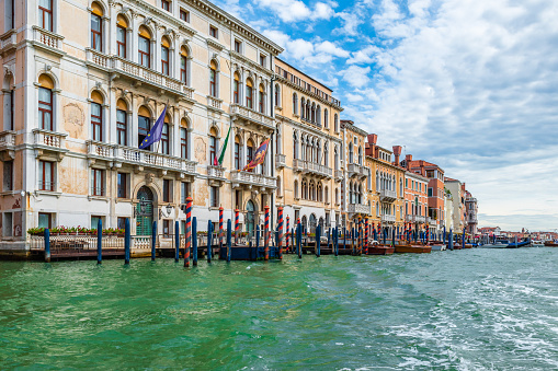 Facades of beautiful old buildings along the Grand Canal in Venice, Italy. Cloudy sky on summer day.