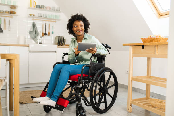 African American woman in a wheelchair using a smart home app on her tablet stock photo