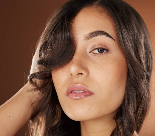 Woman, face skincare or curly hairstyle on brown studio background in color dye advertising, self love or Brazilian keratin treatment. Portrait, beauty model or brunette waves and natural makeup glow cuidado de la piel de la mujer, la cara o peinado rizado sobre fondo de estudio marrón en publicidad de tinte de color, amor propio o tratamiento de keratina brasileña. retrato, modelo de belleza u ondas morenas y maquillaje natural brillan