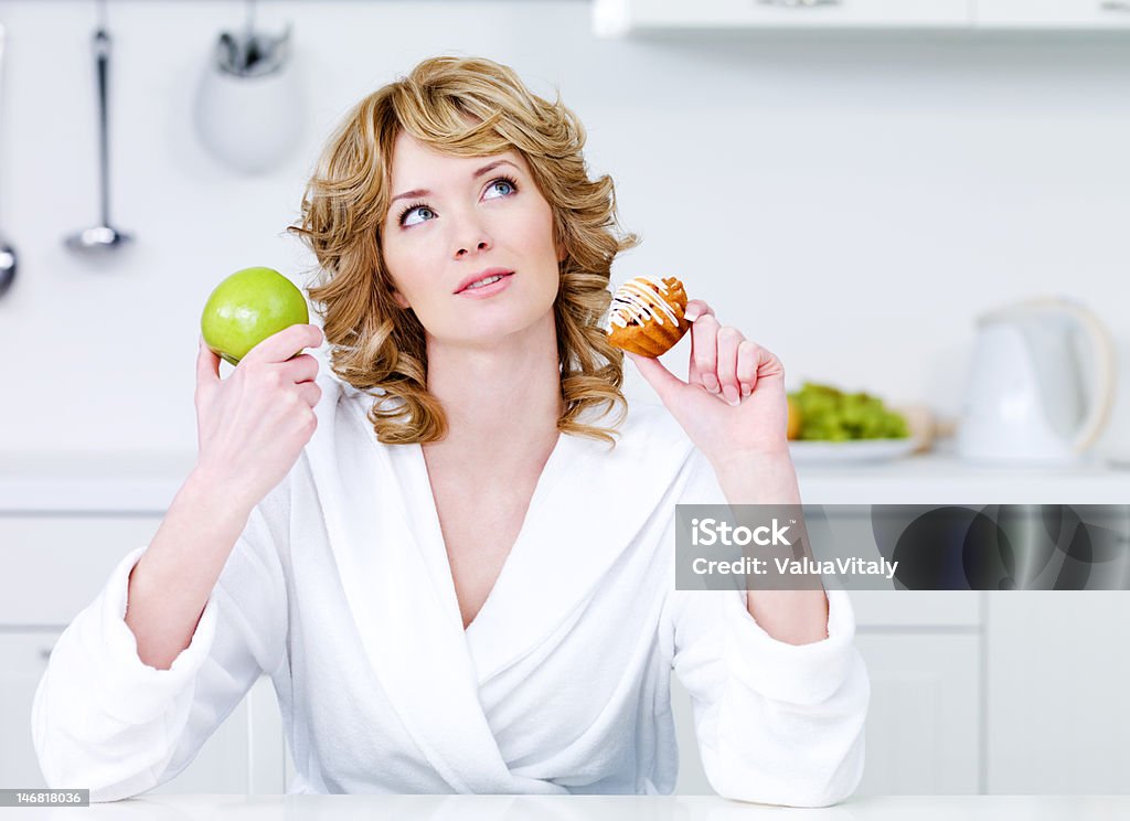 Woman choosing between healthy food and caloric cake Thinking beautiful woman choosing between healthy food and caloric food - indoors 20-29 Years Stock Photo
