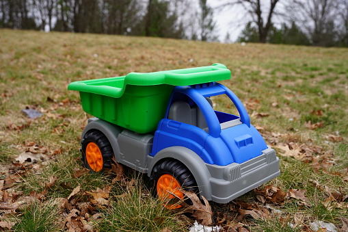 Child's Blue toy dump truck sits outside during the early spring.