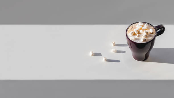 istock Cup of cappuccino with marshmallow. Geometrical minimalist background with coffee mug. Light, shadow and hot beverage with frothy milk on white table. Horizontal banner with copy space. 1468185471