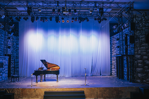 music stage theater with grand piano and white backdrop illuminated with stage light
