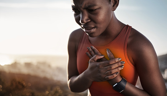 Heart pain, fitness and black woman with an injury from cardio, running and nature workout in Germany. Asthma, health and African runner with heart attack risk during training on the mountain