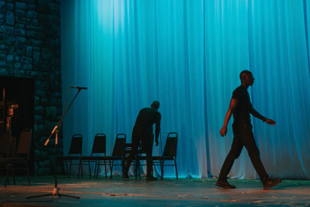 Theatre crew arranging chairs on stage set getting ready for stage performance