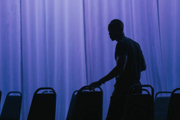 Theatre crew arranging chairs on stage set getting ready for stage performance
