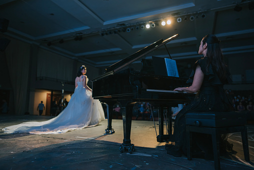 Young Chinese Female opera singer performing solo on stage with pianist