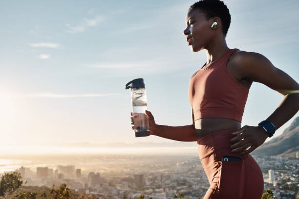 Black woman, water bottle or earphones in running workout goals, healthcare wellness training or sunset city exercise. Fitness drink, sports athlete or runner listening to motivation radio at sunrise mujer negra, botella de agua o auriculares en objetivos de entrenamiento para correr, entrenamiento de bienestar sanitario o ejercicio de la ciudad al atardecer. bebida fitness, atleta deportivo o corredor escuchando radio de motivación al amanecer
