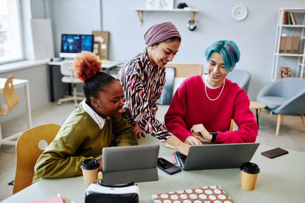 Diverse group of creative young people using laptop during meeting in office