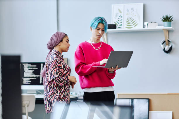 istock Two gen Z young people using laptop white standing in office 1468187304
