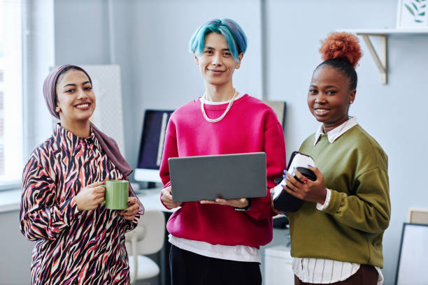 istock Diverse creative team looking at camera standing in office and holding laptop 1468187308