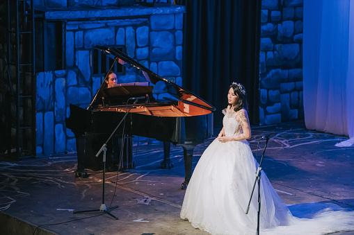 Asian Chinese Female opera singer performing solo on stage with pianist