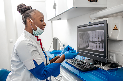 Black female dentist looking at x-rays