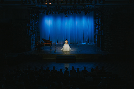 Young Chinese Female opera singer performing solo on stage with Pianist