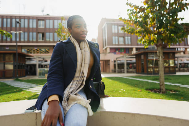 Young businesswoman sitting alone on a park bench during autumn, looking away in deep frustration. She appears stressed, tired and overworked as emotional pressure from her job weighs heavily on her.