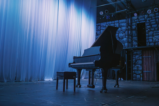 music stage theater with grand piano and white backdrop illuminated with stage light