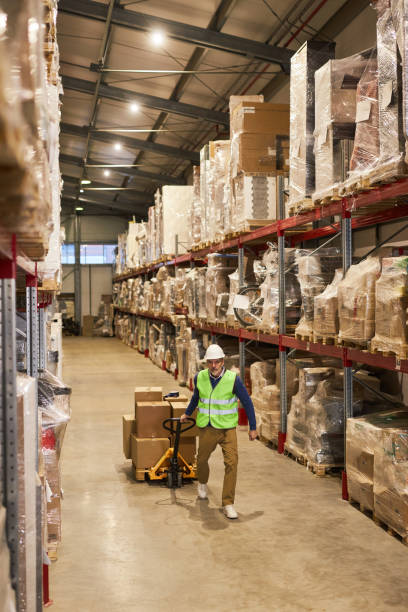 istock Vertical view at warehouse interior with worker pulling cart in row aisle 1468190966