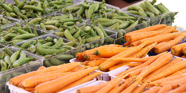 Carrots and sugar snap peas at produce stand stock photo